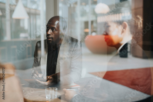 Bald businessman sharing ideas while discussing with female colleague seen through glass photo