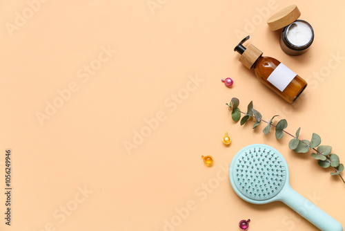 Hair brush with bottle and jar of cosmetic products on orange background