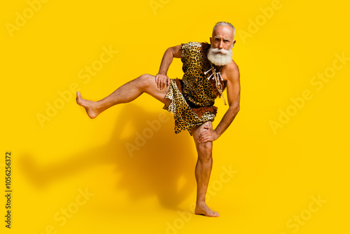 Full length photo of handsome cool neanderthal guy wear leoprad skin dancing rituals emtpy space isolated yellow color background photo