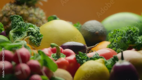 Close up of assortment of fruits and vegetables on orange background. Nutrition and healthy diet concept.