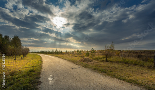 A road with a sun shining through the clouds