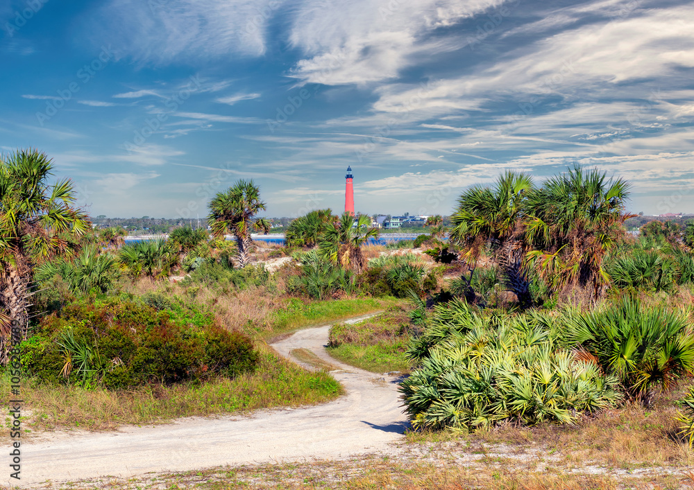 Palm trees on pathway to the beach and Lighthouse Ponce de Leon Inlet in New Smyrna beach, Florida