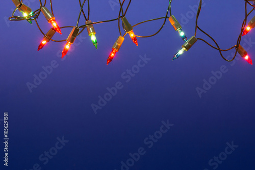 Christmas lights string on blue background with copy space