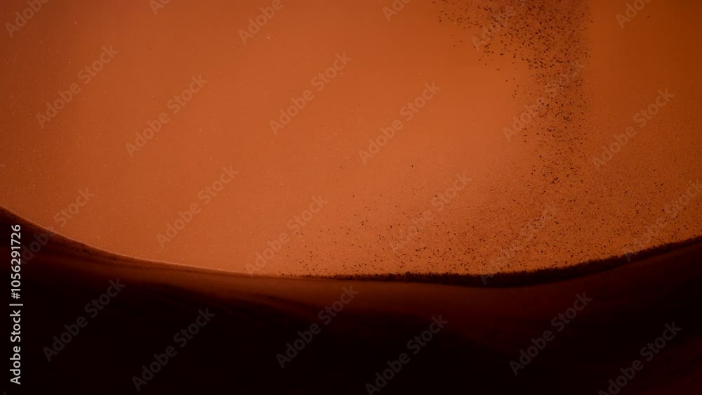 Dust particles falling onto a pile of sand in abstract slow motion. 