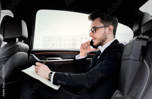 Important Call. Side view of focused businessman planning his day and talking on cell phone, going to office by car