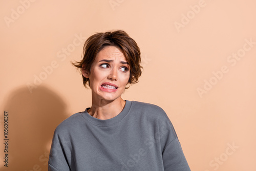 Photo portrait of lovely young lady look nervous astonished empty space wear trendy gray garment isolated on beige color background photo