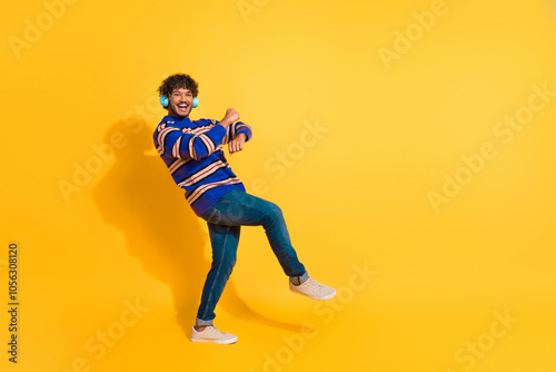 Full body photo of attractive young man headphones dance boogie woogie dressed blue striped clothes isolated on yellow color background