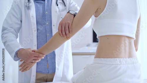 Doctor man examines a patient's elbow during a medical consultat photo