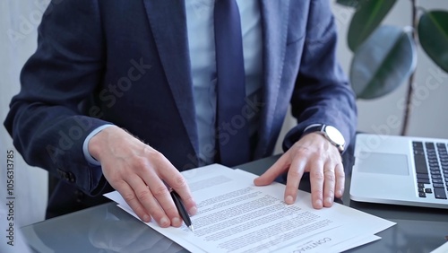 Businessman signing contract at desk. Close-up of a male executive's hands signing a legal document in a modern office setting