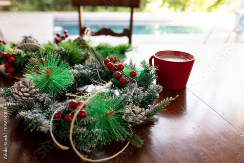 Festive Christmas wreaths and hot cocoa on table by poolside, at home photo