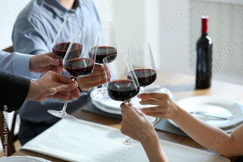 People clinking glasses of wine indoors, closeup