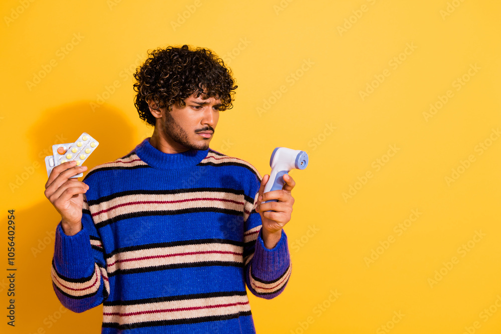 Photo portrait of attractive young man look sad pills thermometer dressed stylish blue striped clothes isolated on yellow color background Photo portrait of attractive young man look sad pills thermometer dressed stylish blue striped clothes isolated on yellow color background
