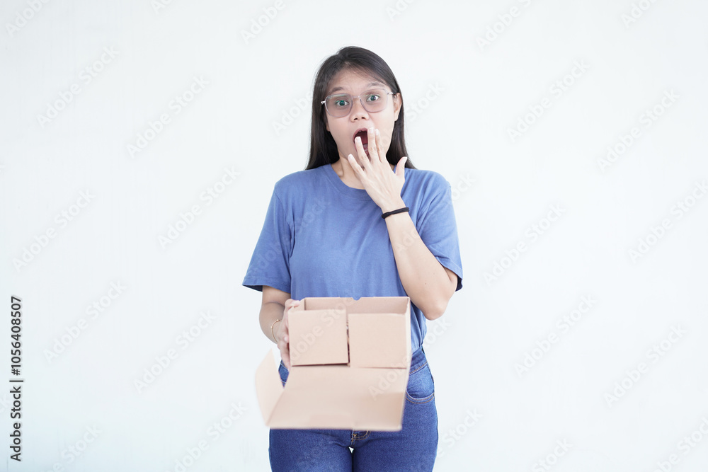 beautiful Asian woman holds a box package, displaying a shocked wow face expression against a white background beautiful Asian woman holds a box package, displaying a shocked wow face expression against a white background
