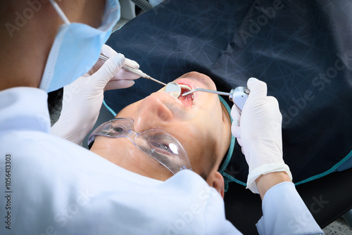 Fotografie A dental professional focuses on the examination of a patient's oral health using specialized tools in a well-lit clinic, providing care and attention during the appointment