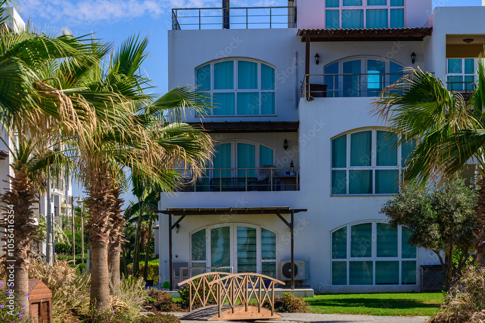 Fototapeta premium Tranquil resort building amidst lush palms and a charming wooden bridge in sunny coastal retreat