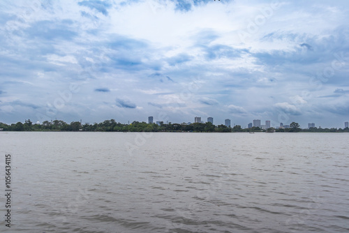 Calm river with a city skyline under a cloudy sky, creating a serene and peaceful scene