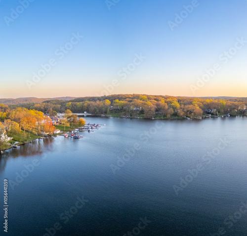 Tranquil sunset over a serene lake, capturing the peaceful reflections of fading sunlight on calm waters with silhouetted trees on the shoreline.