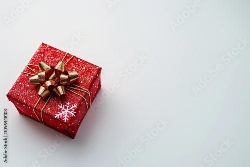 A red box with a gold bow and a snowflake on it. The box is sitting on a white background