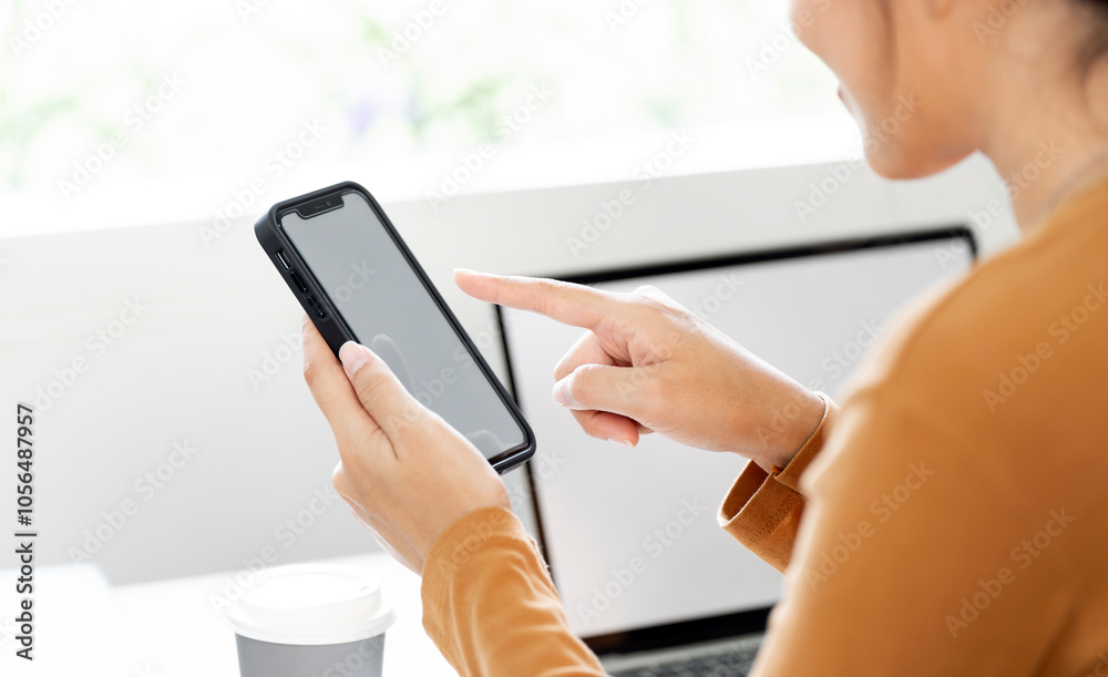 Fototapeta premium Close-up shot of woman's hands tapping on a mobile phone screen
