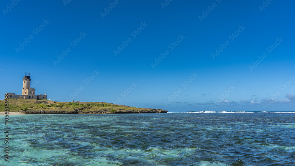 An old lighthouse on a tropical island. A dilapidated building with a high tower. Turquoise ocean, waves foaming in the distance. The blue sky. Copy space. Mauritius. Ile aux Fouquet's An old lighthouse on a tropical island. A dilapidated building with a high tower. Turquoise ocean, waves foaming in the distance. The blue sky. Copy space. Mauritius. Ile aux Fouquet's
