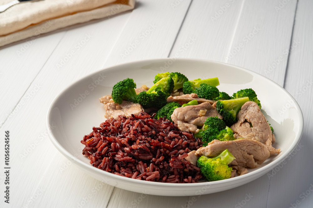 Cooked riceberry rice and Stir fried broccoli with pork tenderloin fillet in white plate.Thai Healthy food for low fat diet menu. Cooked riceberry rice and Stir fried broccoli with pork tenderloin fillet in white plate.Thai Healthy food for low fat diet menu.