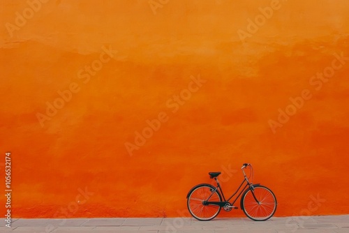 A minimalist bicycle stands against a vibrant orange wall, showcasing a harmonious blend of color and design in an urban setting photo