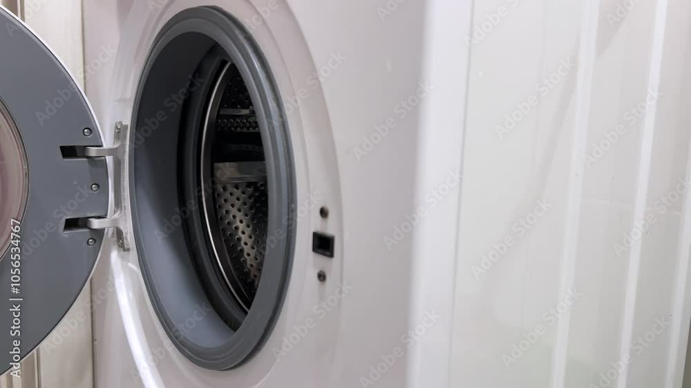 Horizontal 4K video. Close up of male hand putting dirty laundry into white washing machine. Man opens round glass door. Concept of washing red and yellow bed linen, clothes, panties, jeans, t-shirt Horizontal 4K video. Close up of male hand putting dirty laundry into white washing machine. Man opens round glass door. Concept of washing red and yellow bed linen, clothes, panties, jeans, t-shirt