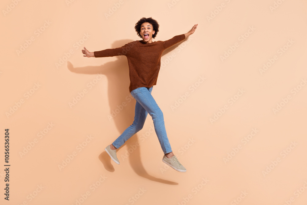 Young man in casual outfit jumps against beige background, expressing excitement and fun embracing youthful energy Young man in casual outfit jumps against beige background, expressing excitement and fun embracing youthful energy