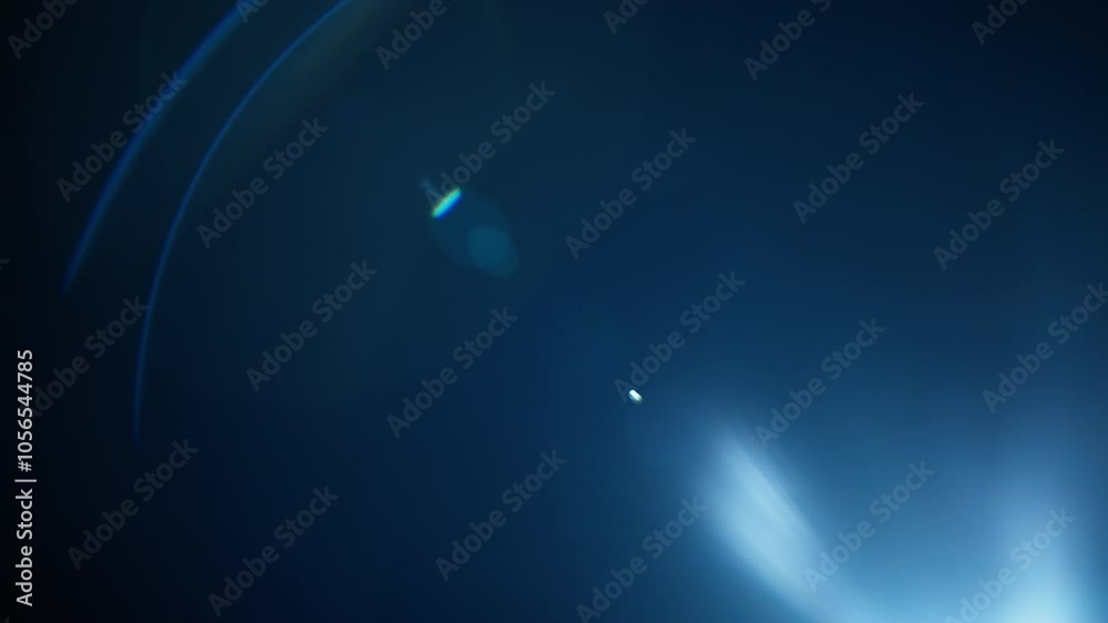 Blue lens flares overlay fading out into black background. Slow motion.