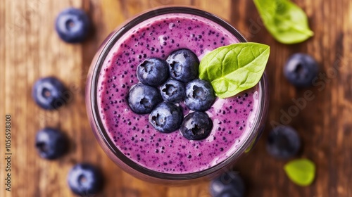 Delicious blueberry smoothie topped with fresh blueberries and a basil leaf on a rustic wooden table. photo