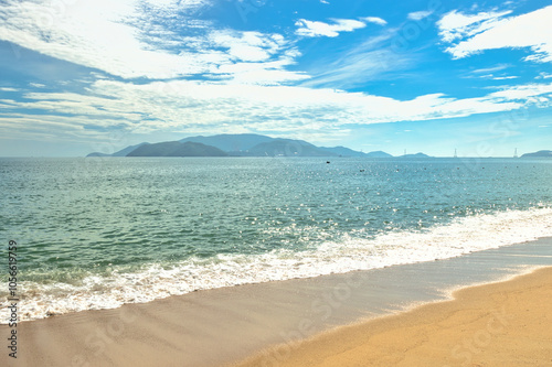 Nha Trang city, Vietnam - October 29, 2024 : Overlooking the beautiful coast of Nha Trang with palm trees on the beach with deck chair and parasol. Beautiful white sand tropical beach in coastal city.