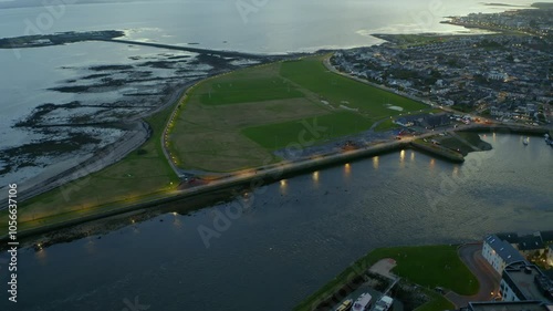 Aerial reverse shot reveals Nimmo's Pier at twilight with lights on, Claddagh, and Galway coast photo