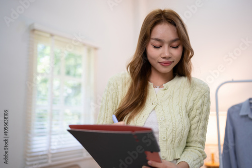 A fashionable woman wearing beautiful attire stands beside a mannequin adorned with trendy clothes as she showcasing from home, showcasing the latest fashion pieces to online customers.