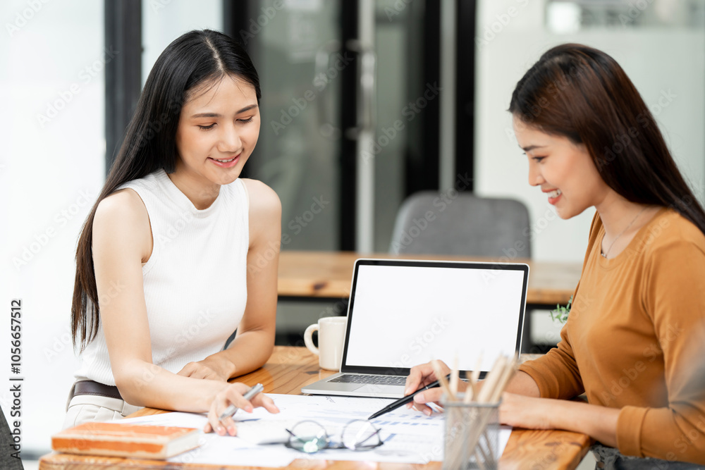 Business women at office desk working together on a laptop, teamwork concept Business women at office desk working together on a laptop, teamwork concept