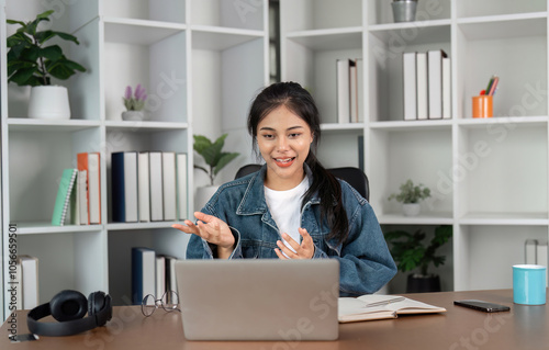 Young Woman Studying Online at Home Using Laptop, Engaged in Virtual Learning, Sitting at Desk with Books and Headphones