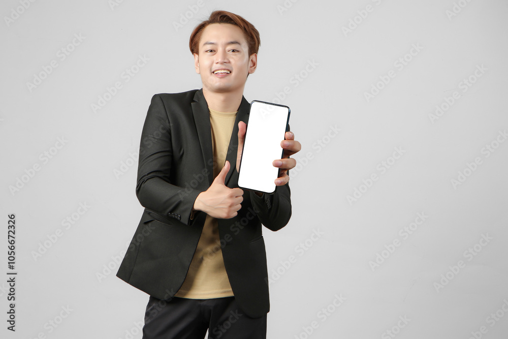 portrait of happy asian businessman wearing suit holding mobile phone and showing blank screen giving thumb up gesture on isolated background. portrait of happy asian businessman wearing suit holding mobile phone and showing blank screen giving thumb up gesture on isolated background.