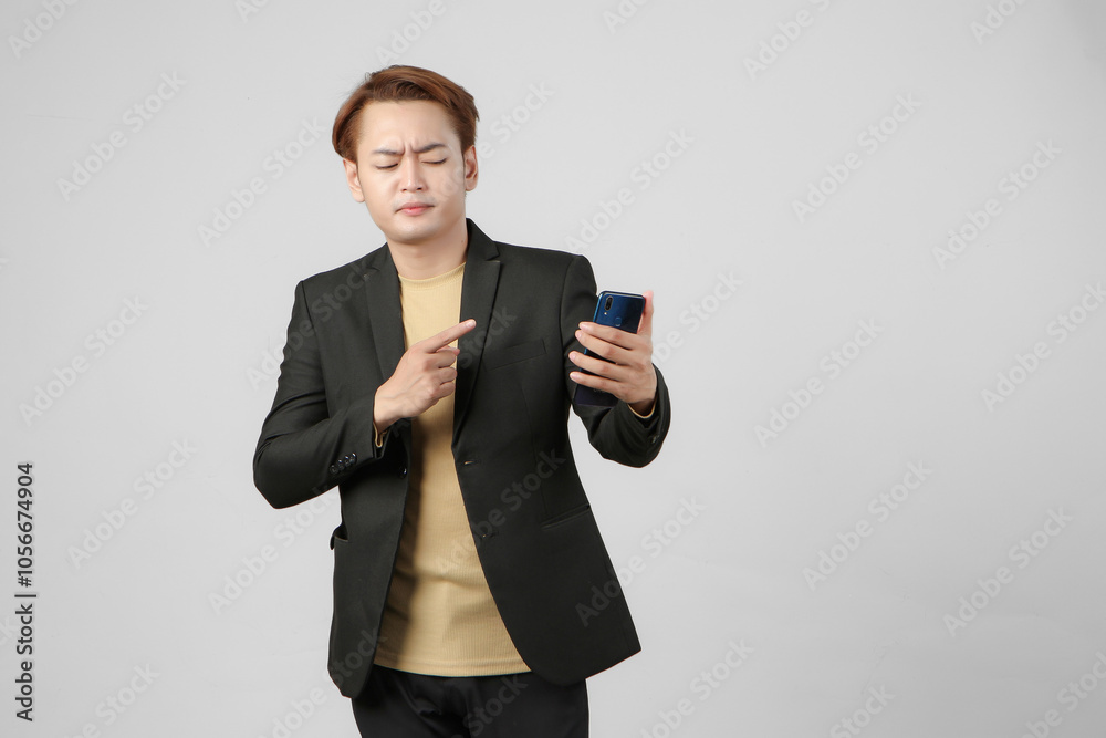 portrait of angry mad asian businessman wearing holding mobile on isolated background