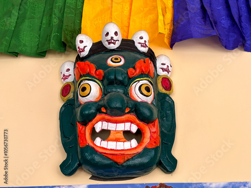 A green mask with red and orange features and skulls on it