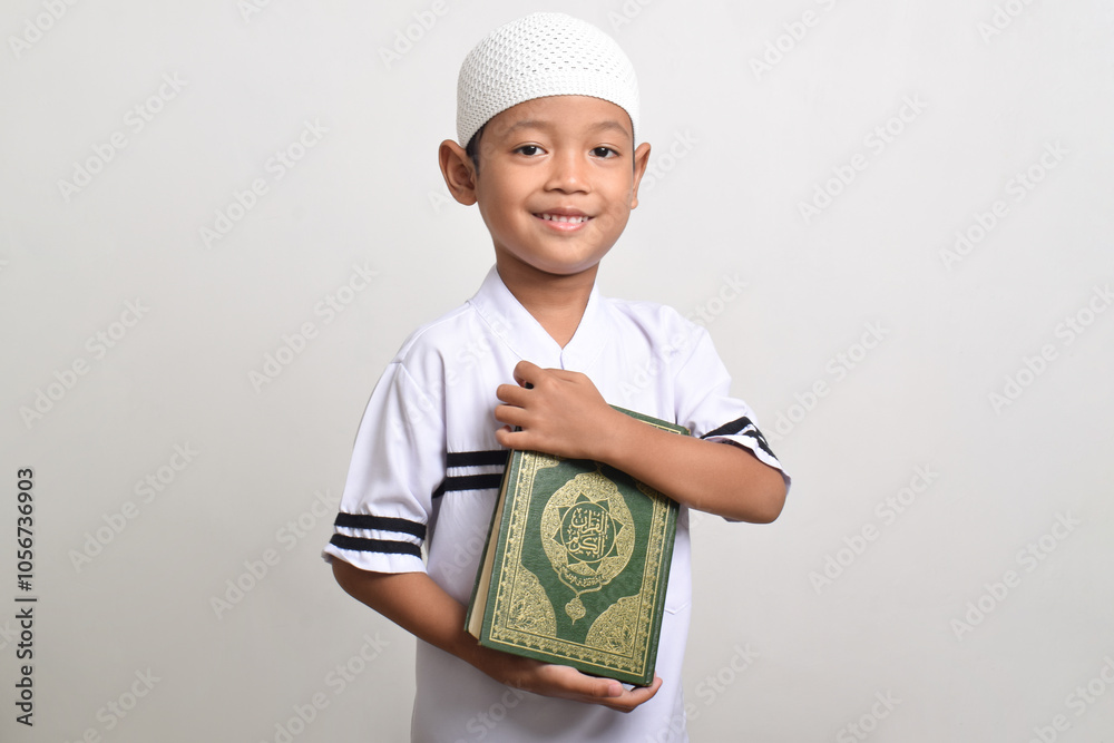 Portrait of smiling Muslim boy holding Quran isolated on white background