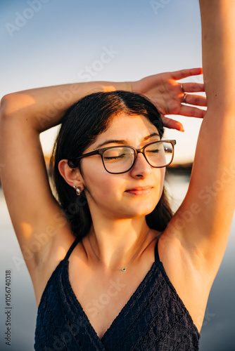 Close-up of woman in glasses with closed eyes, basking in sunset light photo