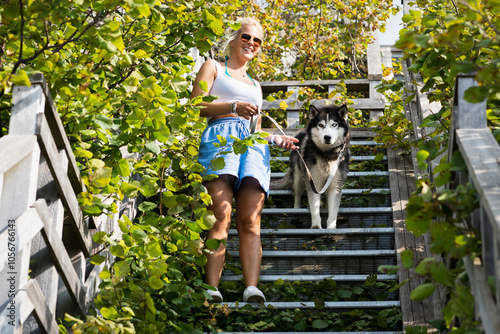 A young European-looking girl with a husky dog ​​walks in nature on the stairs of a traveler's path on a summer day. photo