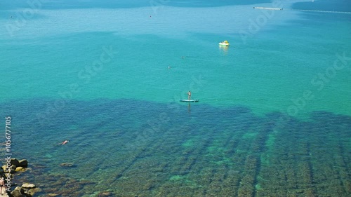 A man on a SUP board in clear sea water. An aerial view of the turquoise sea with a clear distinction between deep blue water and a shallow area with sea grass thickets photo