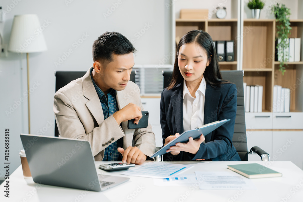 Two business workers talking on the smartphone and using laptop at the office.. Two business workers talking on the smartphone and using laptop at the office..