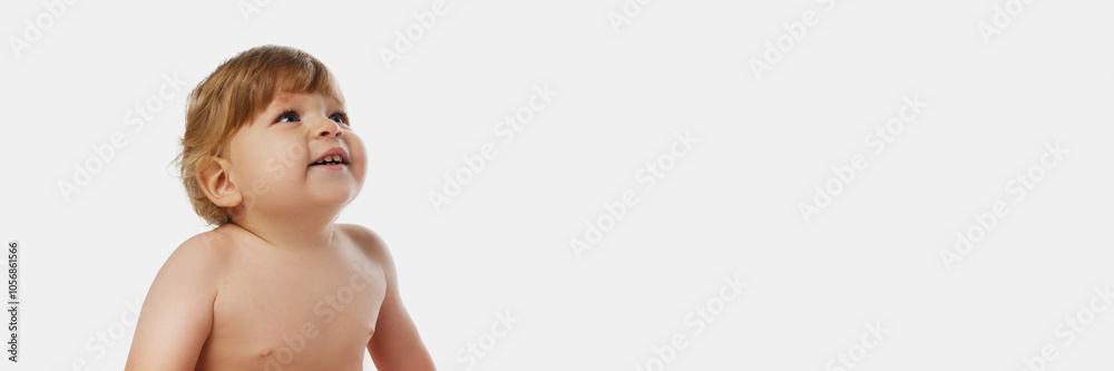 Banner. Charming little kid, baby-boy looking upward with curious gaze against white background with copy space. Baby discovery. Concept of parenthood, natural beauty, love and care. Ad. Banner. Charming little kid, baby-boy looking upward with curious gaze against white background with copy space. Baby discovery. Concept of parenthood, natural beauty, love and care. Ad.
