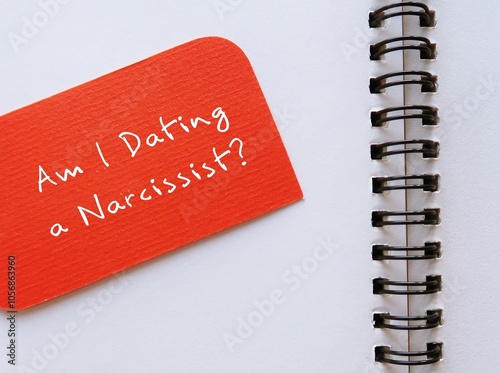 Orange card on notebook written Am I Dating a Narcissist? - question to ask if one have troubled or toxic relationships with narcissistic disorder traits in partner’s personality