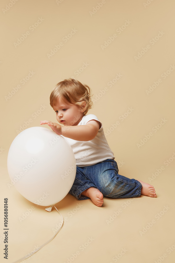 Learning through play. Toddler in casual clothing explores against beige studio background. Little baby-boy. Concept of parenthood, natural beauty, love and care. Ad. Learning through play. Toddler in casual clothing explores against beige studio background. Little baby-boy. Concept of parenthood, natural beauty, love and care. Ad.