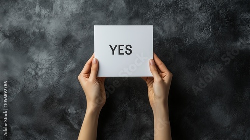 A hand holding a white card with the word yes written on it. Concept of agreement or approval photo