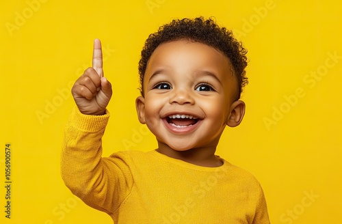 an excited little boy pointing his finger up and having an idea, against a yellow background