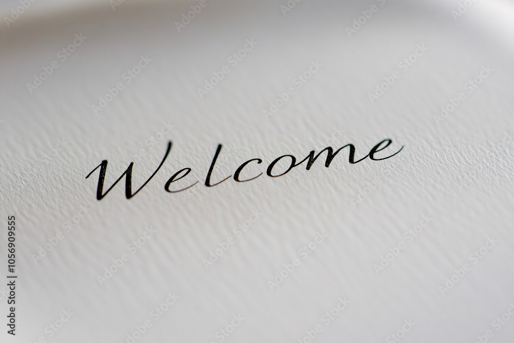 Fototapeta premium closeup of elegant black cursive welcome text on white textured paper evoking warmth and hospitality in a minimalist style 