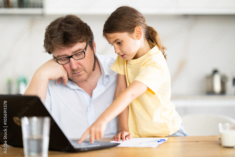 Father helps daughter do homework using laptop Father helps daughter do homework using laptop